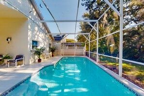 Une piscine entourée d’une clôture blanche, agrémentée de plantes en pot et d’un banc.