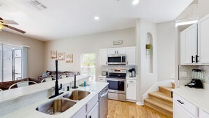 A modern kitchen with white cabinetry, stainless steel appliances, and a wooden floor. - Harmony Villa | Family-friendly home in Davenport with a game room & pool (Davenport)