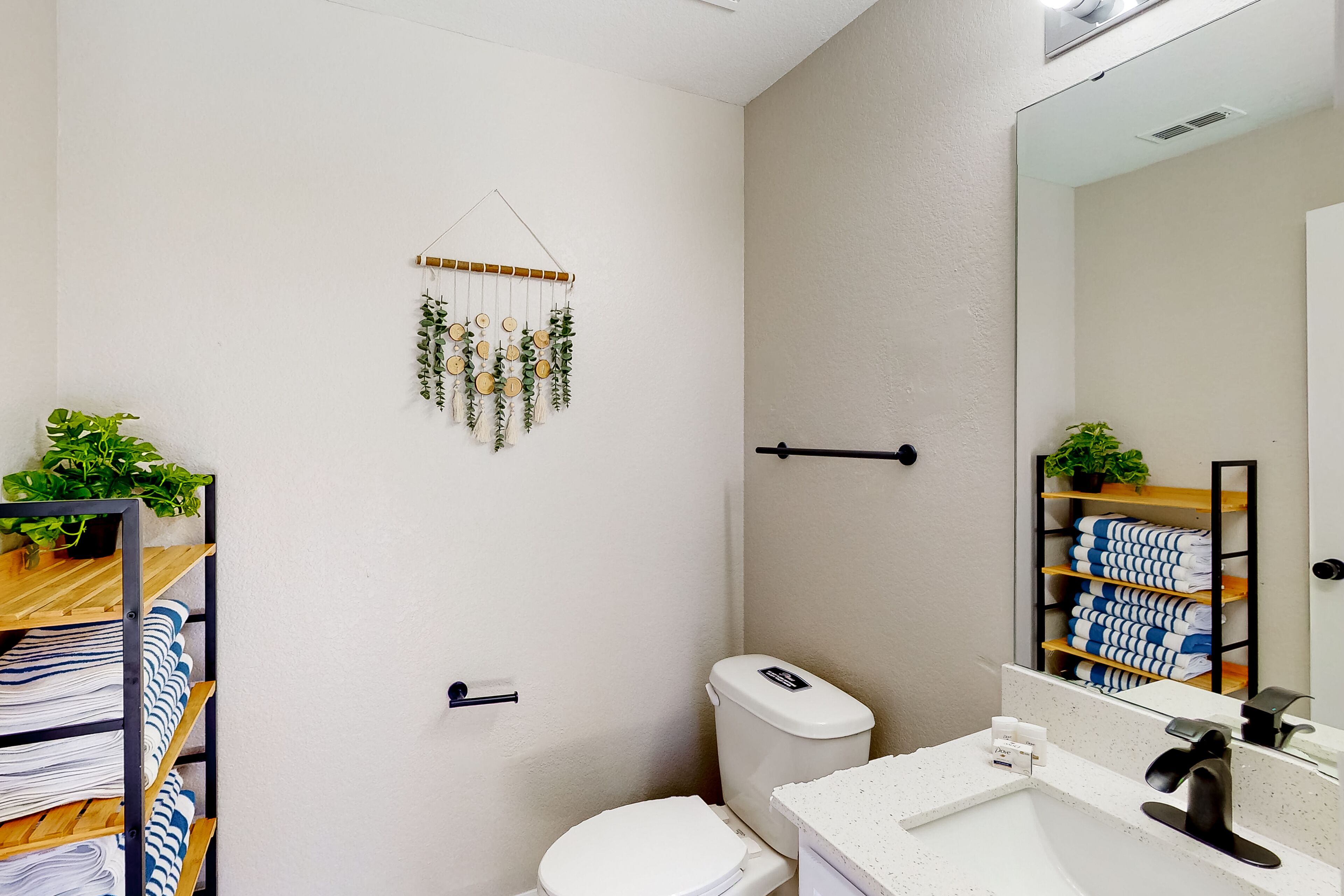 Et moderne badeværelse med toilet, vask og en vægmonteret hylde med håndklæder.