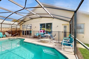 A pool area with a glass enclosure, lounge chairs, and a table. - Seven Dwarfs Hideaway | 4BR Pool Home in Davenport (Davenport)