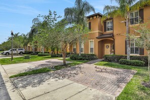 A residential building with a brick pathway, green lawns, and palm trees. - Mermaid Cove 4BR/3BA Davenport Resort Townhouse (Davenport)