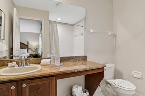 A bathroom with a granite countertop sink, a mirror, a toilet, and a shower area. - Mermaid Cove 4BR/3BA Davenport Resort Townhouse (Davenport)
