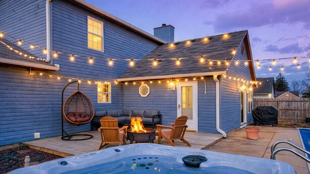 Ein Garten mit Whirlpool, Sitzgelegenheiten im Freien und Lichterketten.
