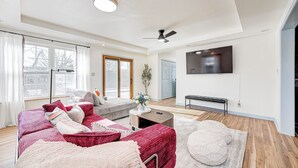 Ein modernes Wohnzimmer mit einer Couch, einem Couchtisch und einem an der Wand montierten Fernseher.