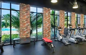 A gym with exercise equipment, large windows, and a view of a pool. - Family-Friendly Home with Private Pool, WiFi, Central AC, & Private Washer/Dryer (Davenport)