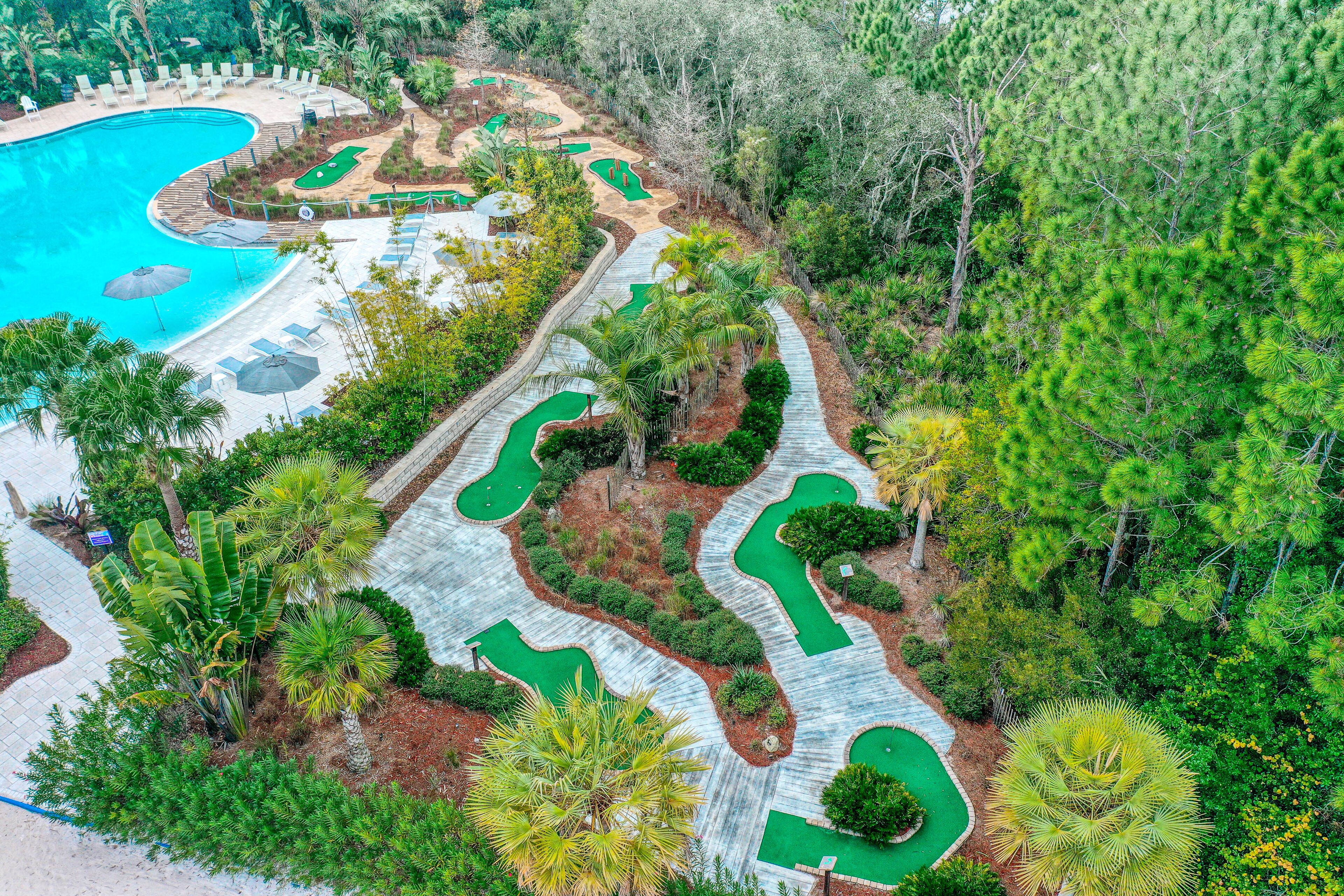 Un campo de golf con piscina, rodeado de exuberante vegetación y palmeras.