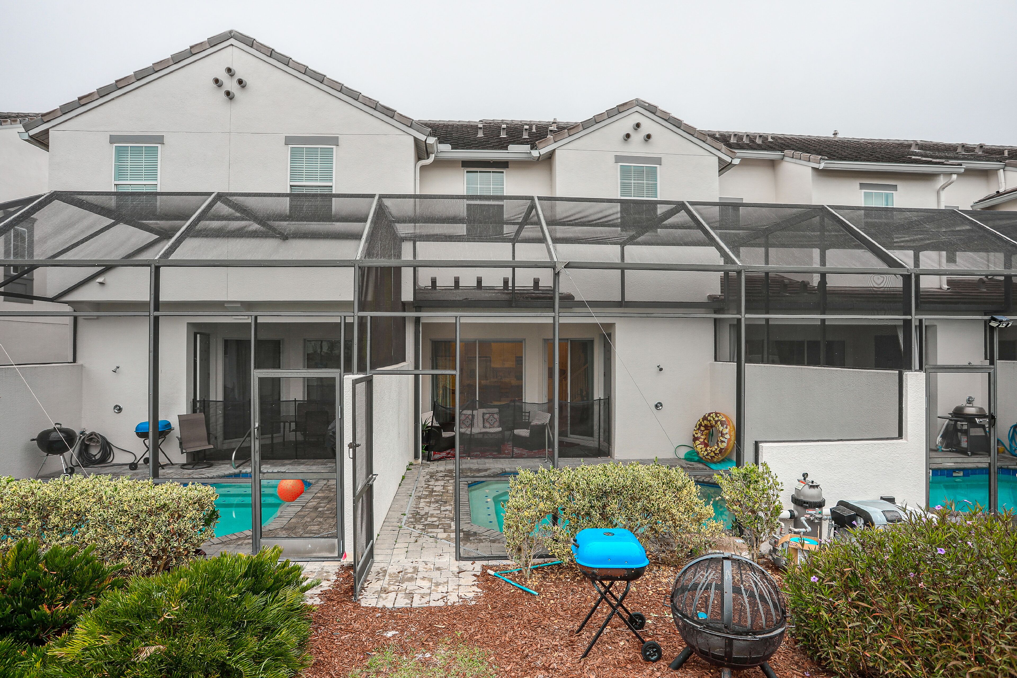 Un immeuble résidentiel doté d’un patio couvert, d’une piscine et de divers meubles d’extérieur.