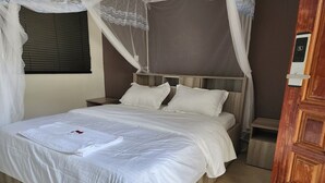A bed with white linens, a wooden headboard, and a canopy.