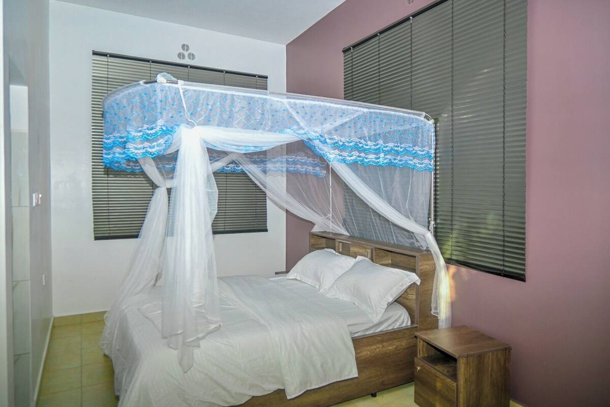 Ein Schlafzimmer mit einem hölzernen Bett, weißer Bettwäsche und einem Baldachin.