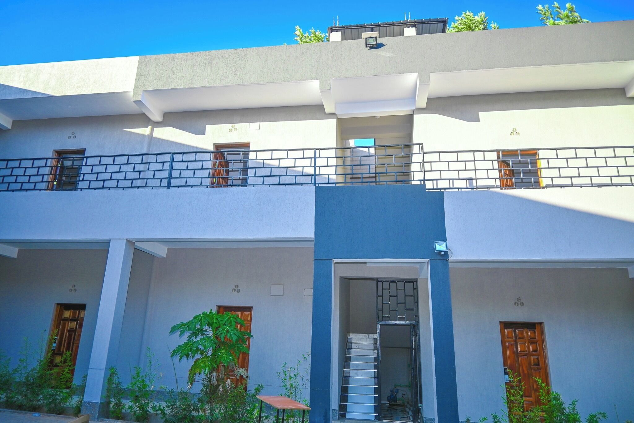 A modern two-story building with a balcony, a staircase, and a door.