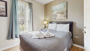 Una habitación de hotel con cama, un cuadro, una lámpara y una ventana con cortinas.