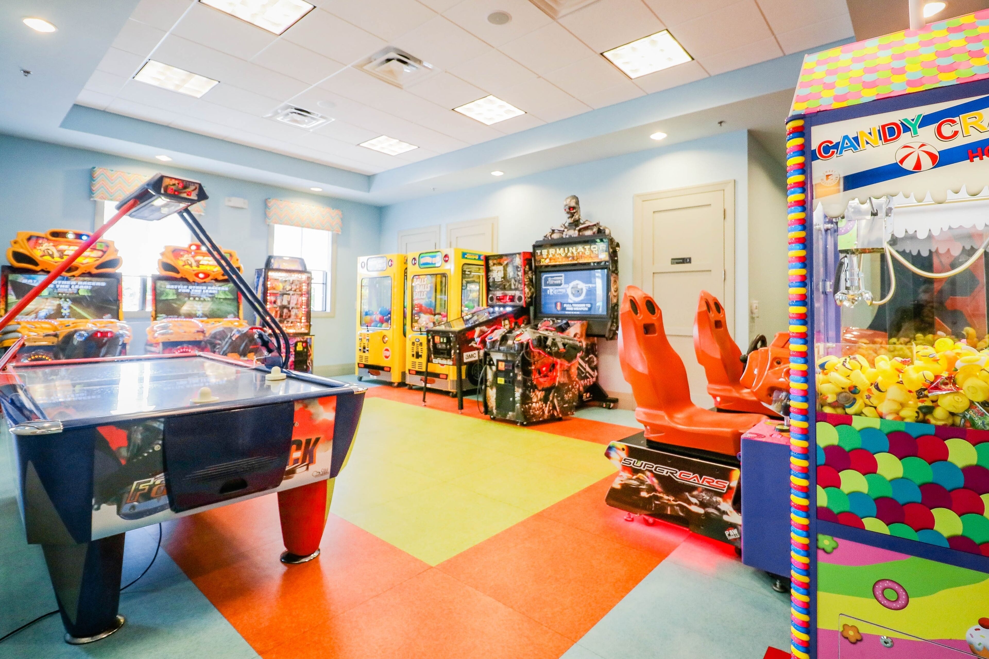 Een helder verlichte speelhal met diverse spelautomaten, waaronder een pooltafel en grijpmachines.