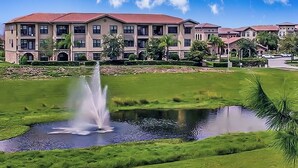 A multi-story hotel with a red roof, a fountain in the courtyard, and well-maintained green lawns. - Dog-friendly condo on ground floor with fast WiFi, shared pool, hot tub, & W/D (Davenport)