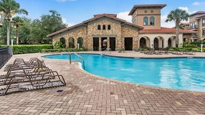 A pool area with lounge chairs and a stone building with arched doorways. - Dog-friendly condo on ground floor with fast WiFi, shared pool, hot tub, & W/D (Davenport)