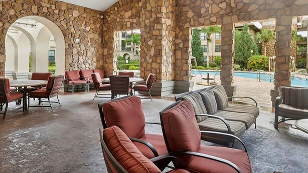 A covered outdoor seating area with stone walls, tables, and chairs. - Dog-friendly condo on ground floor with fast WiFi, shared pool, hot tub, & W/D (Davenport)