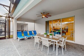 A patio area with a table and chairs, a ceiling fan, and a glass door leading to an interior space. - Spacious private home w/ private pool, resort style waterpark & mini golf access (Davenport)
