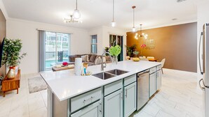 Una cucina moderna con un'isola grande, elettrodomestici in acciaio inossidabile e illuminazione a sospensione.