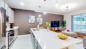 Una cucina moderna con una grande isola, elettrodomestici in acciaio inossidabile e illuminazione a sospensione.