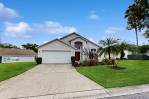 A single-story house with a garage, a front lawn, and a palm tree. - 4BR Tropical Days in Davenport Gated Community, Pool (Davenport)