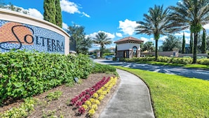 A hotel entrance with a mosaic sign, a pathway, and well-maintained landscaping including hedges and flowers. - Townhome with private pool in Solterra resort, ADA friendly (Davenport)
