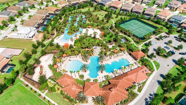 An aerial view of a residential area with a central swimming pool, tennis courts, and a landscaped park. - Townhome with private pool in Solterra resort, ADA friendly (Davenport)
