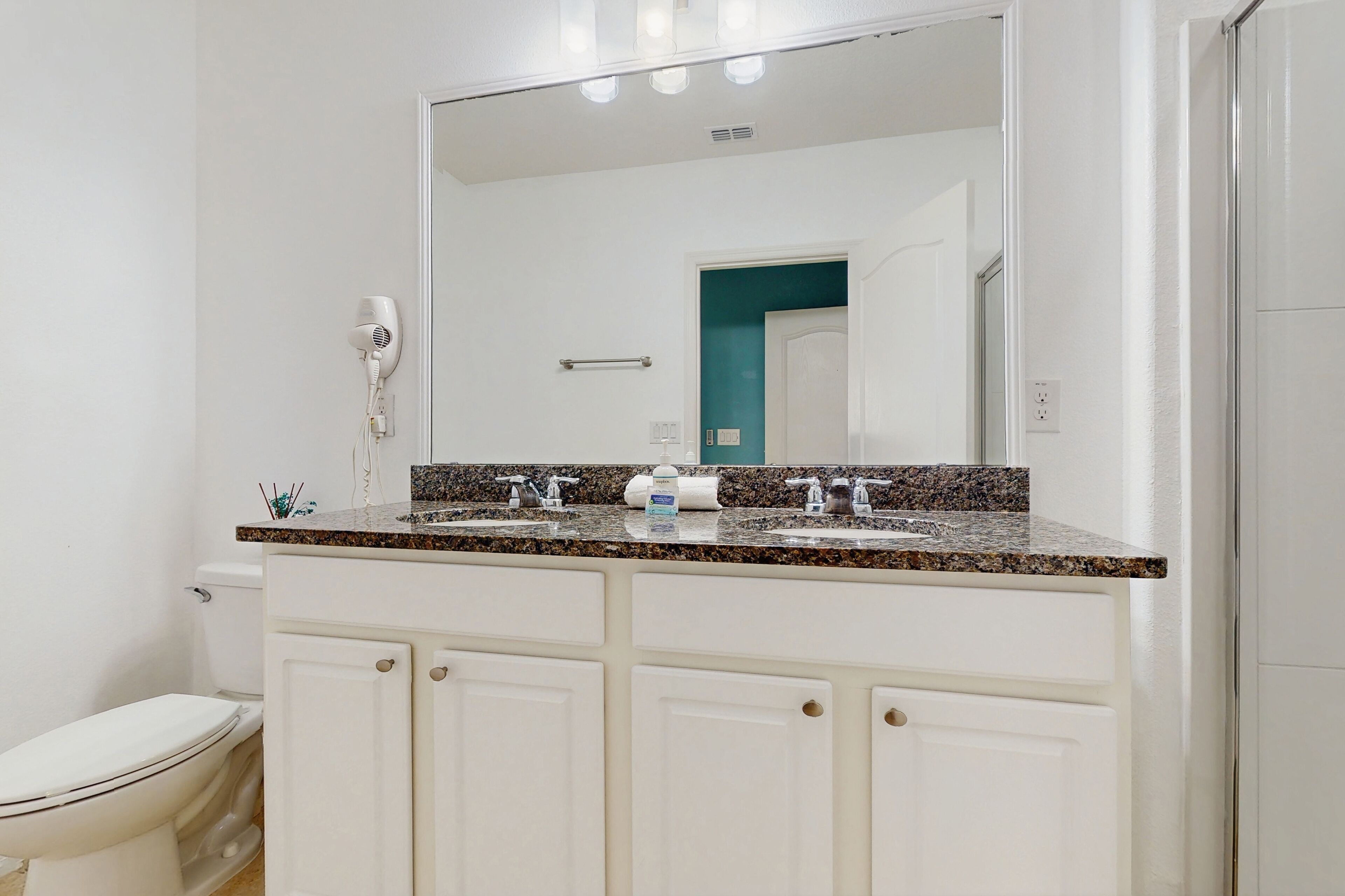 Une salle de bain équipée d’un meuble-lavabo à deux vasques, d’un sèche-cheveux et d’un miroir au-dessus du lavabo.