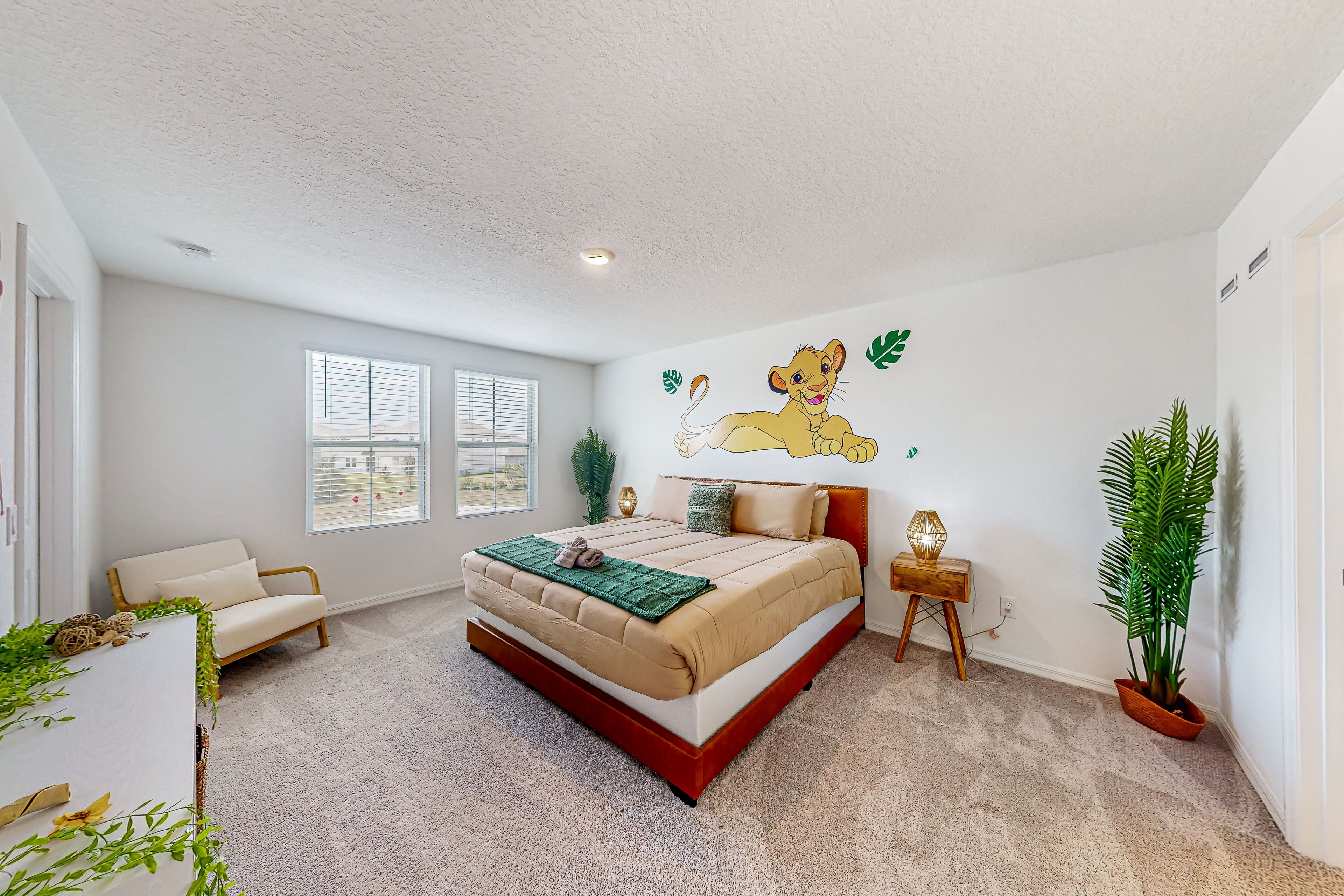 Ein Schlafzimmer mit einem großen Bett, einer Couch, einer Wandmalerei und zwei Fenstern.