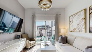 A modern hotel room with a large flat-screen TV, a sofa, a coffee table, and a glass dining table. - Two-story townhouse with private pool, screened lanai, washer/dryer (Davenport)