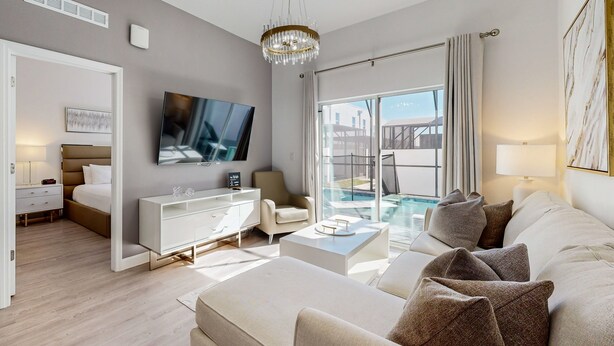 A modern living room with a sofa, a TV, a coffee table, and a glass door leading to a pool area. - Two-story townhouse with private pool, screened lanai, washer/dryer (Davenport)