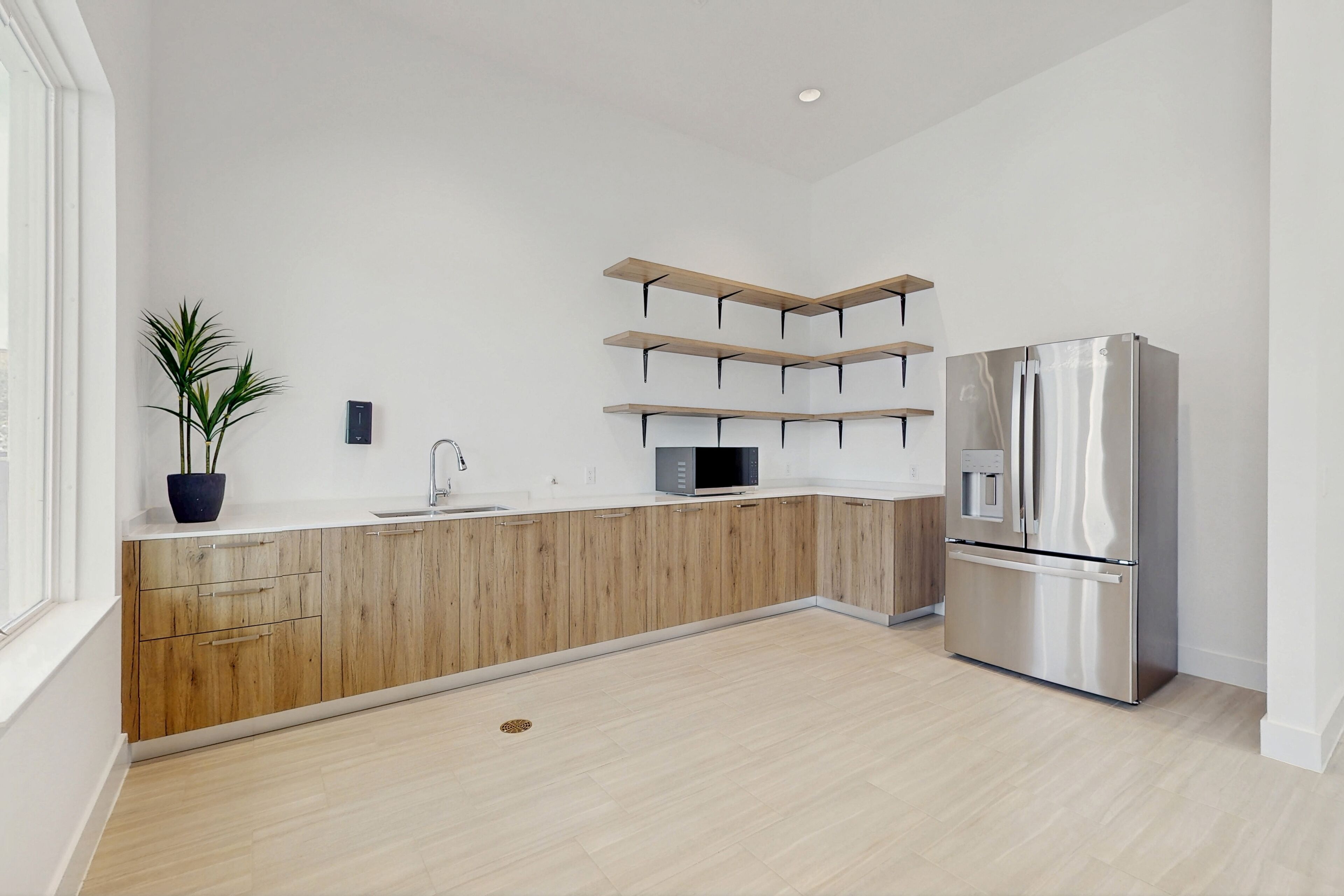 Eine moderne Küche mit Holzausstattung, einem Edelstahlkühlschrank und eingebauten Regalen.