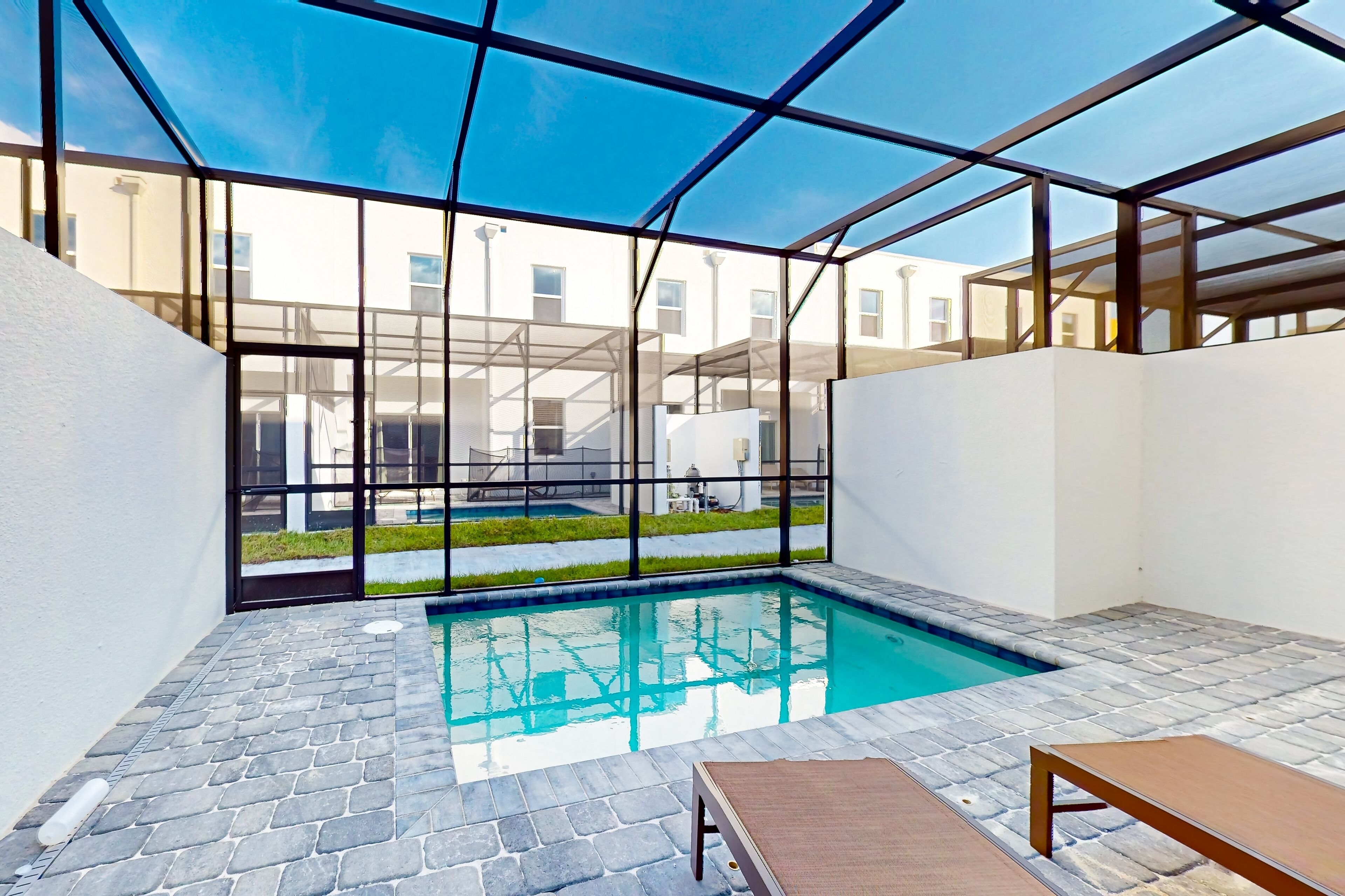 Ein moderner Innenpool mit großen Glaswänden, Steinböden und einer Lounge-Ecke mit einer Sitzbank.