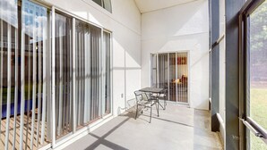 A covered outdoor patio with a table and chairs, large sliding glass doors, and a view of a backyard. - Spacious home in cute area with central AC & washer/dryer - snowbirds welcome (Davenport)