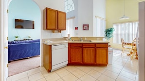 A modern kitchen with wooden cabinets, a built-in dishwasher, and a dining area with a table and chairs. - Spacious home in cute area with central AC & washer/dryer - snowbirds welcome (Davenport)