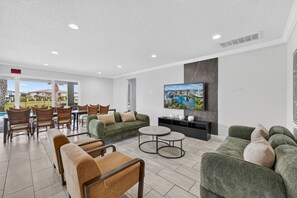 Ein stilvoller Lounge-Bereich mit Sitzgelegenheiten, einem Flachbildfernseher und Blick auf die Stadt.
