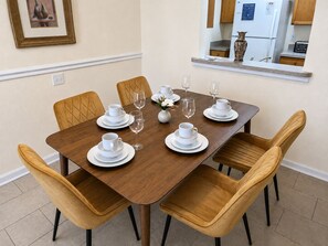 Un coin repas avec une table en bois dressée pour quatre personnes, entourée de quatre chaises.