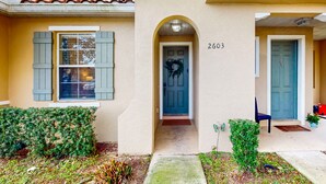 A building with a number 2603 on the wall, a blue door, and a wreath on the door. - Dog-friendly townhouse near Disney with outdoor pool, patio, streaming, W/D, AC (Kissimmee)