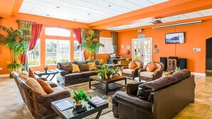 A spacious lobby with orange walls, a large seating area with sofas and chairs, a coffee table, and potted plants. - Family Home w/Shared Pool,WiFi,AC,Lake Views - Close to Walt Disney World Resort (Kissimmee)