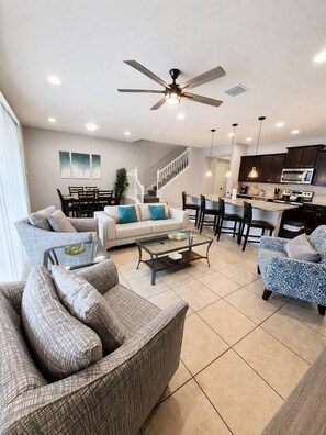 A modern living room with a sofa, coffee table, and dining area. - Limited-Time Special Discounts | Spacious Home w/ Pool and Resort Amenities (Kissimmee)
