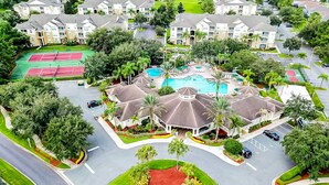 An aerial view of a residential area with a swimming pool, tennis courts, and a landscaped courtyard. - Resort home with private pool, hot tub, tennis, game room, gym, sports courts (Kissimmee)