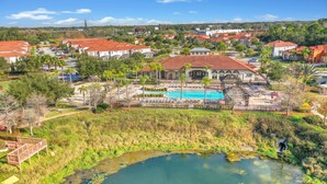 Zona residencial con piscina, un pequeño estanque y casas con tejados rojos.