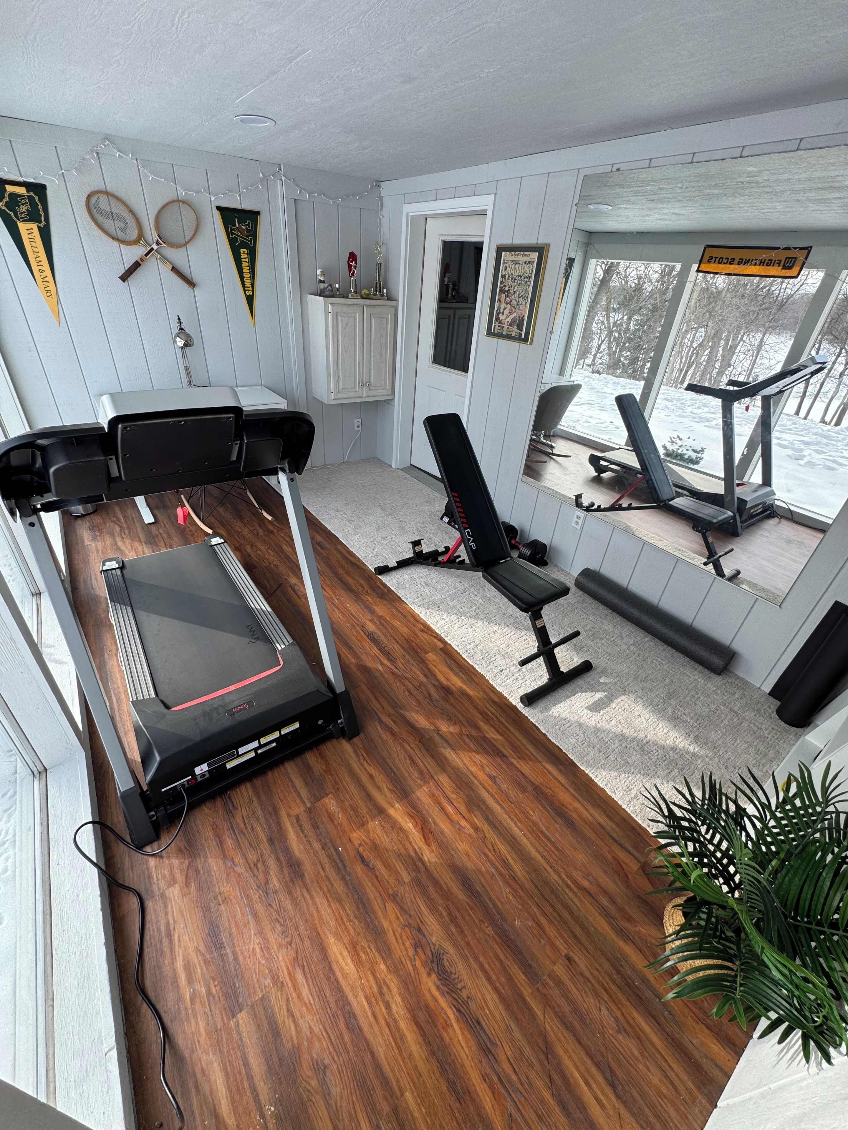 A home gym with a treadmill, exercise bike, and bench.