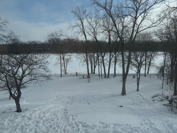 A snow-covered park with bare trees and a frozen lake. - Cozy riverside 1-bedroom retreat in uptown Maumee! (Maumee)