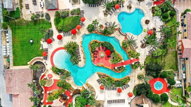 An aerial view of a resort with multiple swimming pools, sun loungers, and palm trees. - Dog-friendly townhouse with heated pool, lazy river, hot tub, game room, BBQ (Davenport)