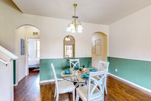 A dining area with a round glass table, white chairs, teal tableware, and a chandelier. - Davenport Sweet Delight | 3BR/3BA Resort Townhome (Davenport)