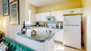 A compact kitchen with white cabinets, a microwave, a stove, and a refrigerator. - Dog-friendly townhouse with heated pool, lazy river, hot tub, game room, BBQ (Davenport)