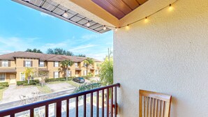 A balcony with a wooden chair, a metal railing, and string lights. - Dog-friendly townhouse with heated pool, lazy river, hot tub, game room, BBQ (Davenport)
