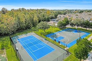A tennis court with a fence, surrounded by trees and residential buildings. - Snowbird-friendly condo near Disney & Orlando with outdoor pool, fast WiFi, W/D (Kissimmee)