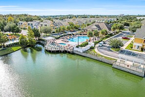 A residential area with a swimming pool, a dock, and a bridge over a canal. - Snowbird-friendly condo near Disney & Orlando with outdoor pool, fast WiFi, W/D (Kissimmee)