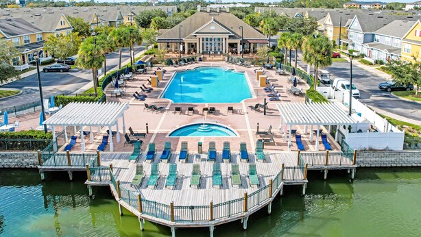 Un resort con piscina central, zonas de descanso y un muelle que se adentra en una masa de agua.