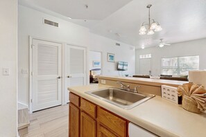 A kitchen with a large island, a double door, and a ceiling fan. - Snowbird-friendly condo near Disney & Orlando with outdoor pool, fast WiFi, W/D (Kissimmee)